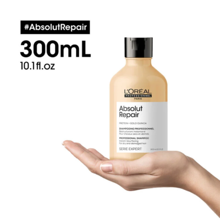 Une main tenant une bouteille de 300 ml de L'Oréal Professionnel Paris ABSOLUT REPAIR SHAMPOING Restructurant Instantané sur un fond blanc. dakar, Sénégal