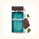 Flacon de parfum avec étiquette "Yves Rocher Eau de Toilette Homme Bois de Sauge 100ml", à côté de feuilles de sauge et d'un petit morceau de bois, rappelant l'Univers Cosmetix au Sénégal.