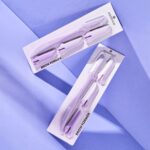 Deux outils Essence Brow Former Rasoir Sourcils 1 Pièce dans un emballage violet sur fond lavande avec des ombres diagonales, mettant en valeur la qualité associée à Univers Cosmetix.