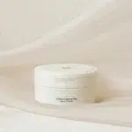 Un récipient blanc étiqueté « Beauty Of Joseon Radiance Baume Nettoyant Hydratant et Illuminateur 80g » repose sur un fond en tissu clair. dakar, Sénégal