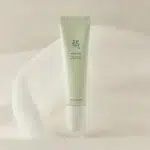 Un tube vert pâle de soin « Beauté de Joseon Sérum Léger à la Vitamine C Unifiant, Éclat Teint 30 ml » se tient debout sur un tissu doux et de couleur claire. dakar, Sénégal