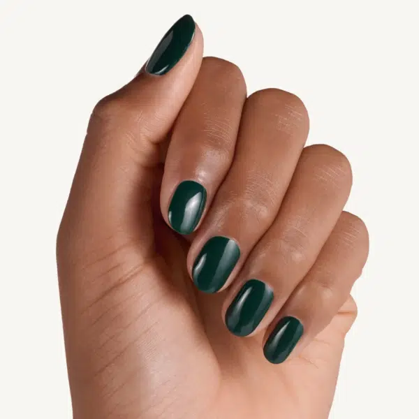 Une main avec des ongles soigneusement manucurés peints en vert foncé Essence Cosmetics Vernis à Ongles 60 Kale Yeah 8 ml vernis à ongles sur un fond clair.