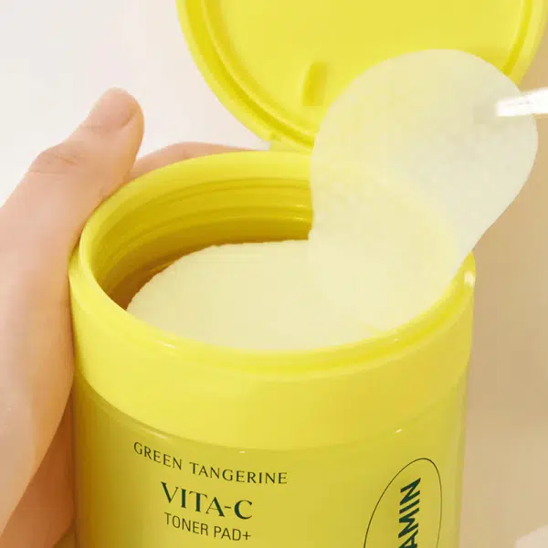 Personne tenant un contenant jaune de Goodal Tampons Tonifiantes Vita C Vert Mandarine Exfoliantes Anti Pores Dilatés Peau Grasse (70 pièces), un tampon étant retiré à l'aide d'une pince à épiler.