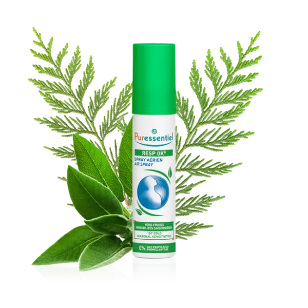 Un flacon de PURESSENTIEL Spray Aérien Resp'OK 20 ml avec en arrière plan un feuillage vert et des herbes.