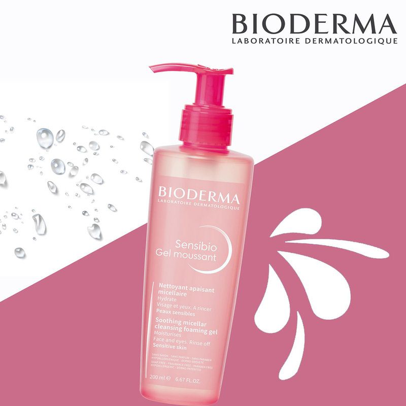 Flacon pompe rose de Bioderma Créaline Gel Moussant Hydratant Peau Sensible 200 ml avec gouttelettes d'eau et logo de la marque sur fond blanc et rose