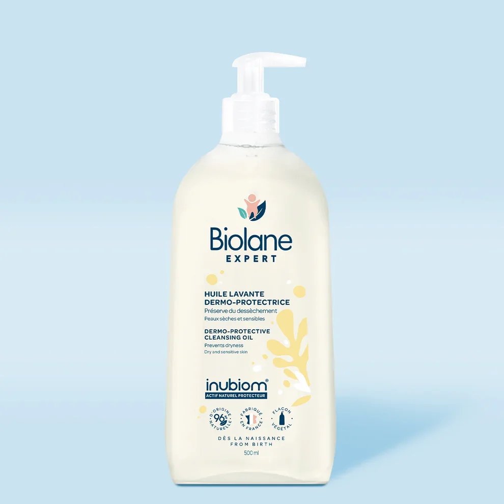 Huile Lavante Dermo Protectrice Biolane Expert dans un flacon pompe transparent sur fond bleu clair.