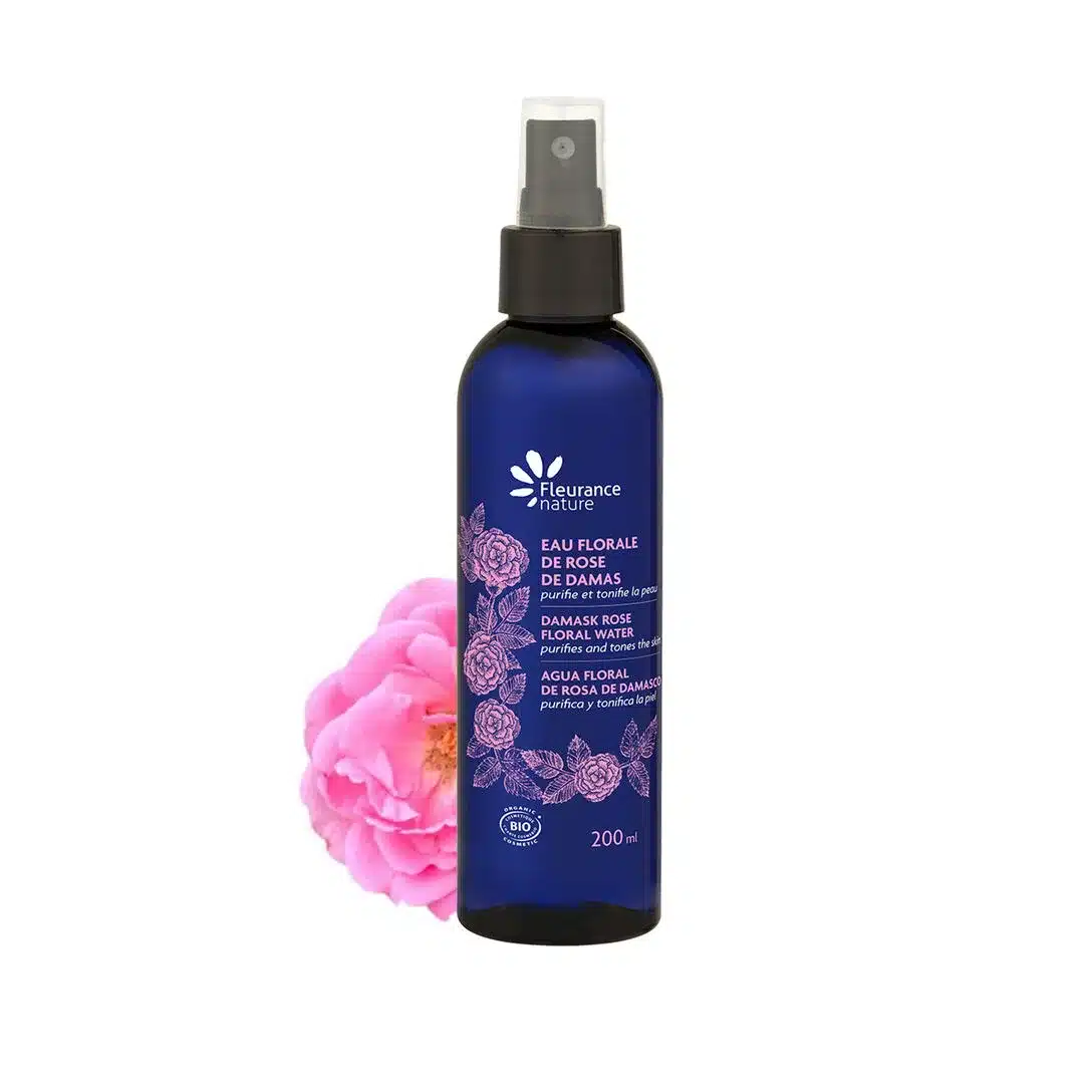 Un flacon de 200 ml de Fleurance Nature Eau florale de Rose de Damas avec une rose rose à côté sur fond blanc