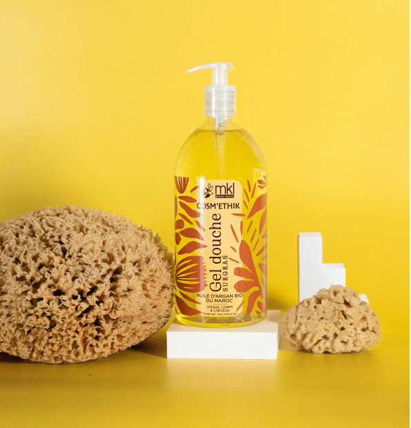 Une bouteille de MKL Cosm'ethik Gel Douche Huile d'Argan du Maroc 1L est élégamment placée sur un socle blanc