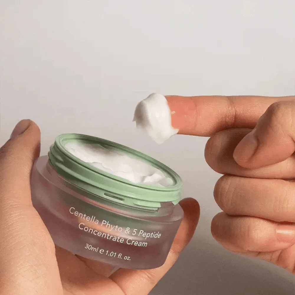 Main trempant dans un pot de Haruharu Wonder Centella Crème Hydratant Concentrée 5 Peptides