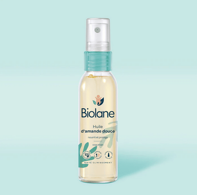 Un flacon de Biolane Spray d'huile d'amande douce 75ml avec une buse de pulvérisation sur fond bleu clair