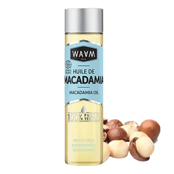 Une bouteille d'huile de macadamia étiquetée "Waam Huile Macadamia BIO 75 ml" avec des noix de macadamia à côté