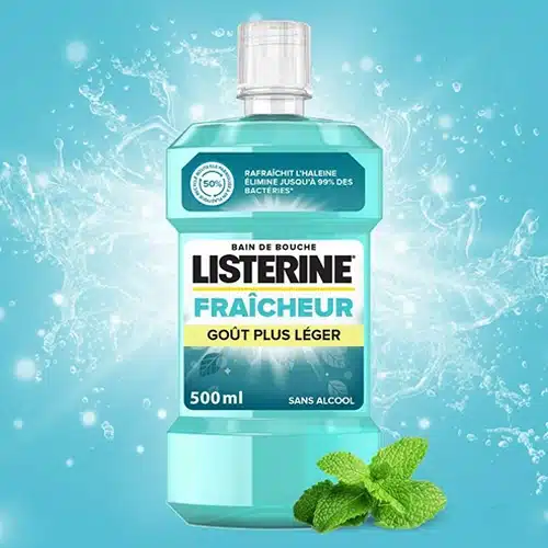 Une bouteille de LISTERINE Bain de Bouche Fraicheur Goût Plus Léger au milieu d'éclaboussures d'eau et de feuilles de menthe fraîche