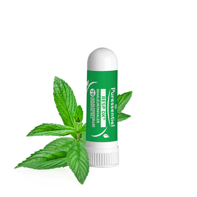 Un Puressentiel Inhaleur Respiratoire 1 ml de couleur verte est placé à côté de feuilles de menthe sur un fond blanc épuré. dakar