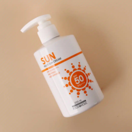 Un flacon de Missha Sun Milk avec pompe sur fond clair met en valeur ses caractéristiques telles que « SPF 50 » et « PA+++ ». Ce flacon blanc orné de touches orange et d'un motif soleil se trouve à côté de la Crème Solaire Clarifiante et Anti Age Foodaholic Multi SUN, d'une contenance de 250 ml. Dakar