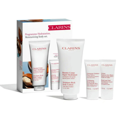 Coffret hydratant corps Clarins comprenant quatre produits : un grand tube de lait corporel, un petit tube, une crème exfoliante et une crème de soin mains et ongles. L'emballage présente le nom de la marque et les informations produit. Dakar