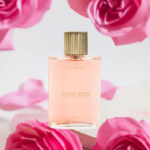Un flacon de parfum rose, étiqueté « Royal Rose », avec un bouchon doré, est placé au milieu de pétales et de fleurs d'un rose tendre. L'arrière-plan est flou, créant une atmosphère romantique et élégante. Dakar