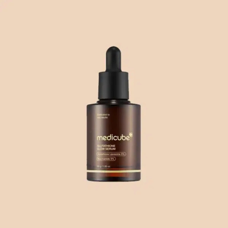 Flacon compte-gouttes en verre de sérum éclat au glutathion Medicube avec une étiquette marron foncé et un bouchon noir sur fond beige. Dakar