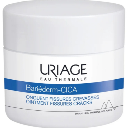 Un pot blanc portant l'inscription « Uriage Eau Thermale Bariéderm-CICA ». Le texte indique qu'il s'agit d'un onguent pour les fissures et les crevasses. Le pot est orné d'une bande bleue et d'un motif de montagne au fond. Dakar