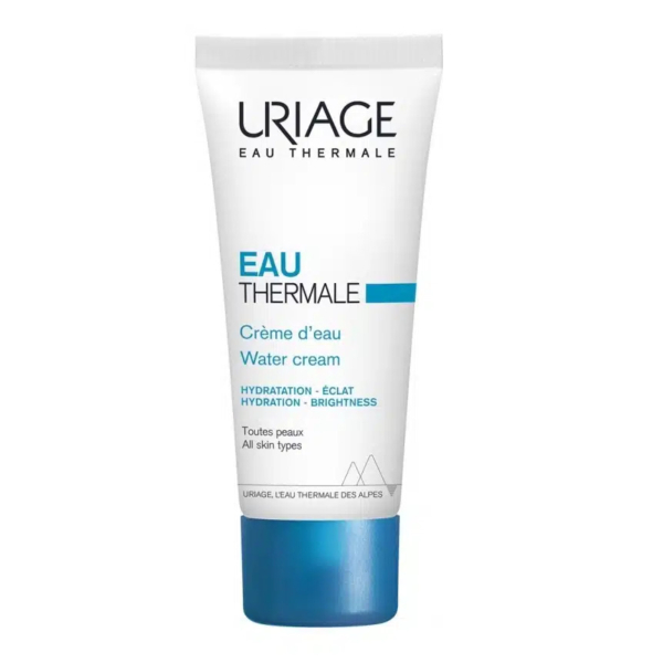 Tube blanc et bleu de crème d'eau Uriage Eau Thermale. Les inscriptions incluent « Crème d'eau », « Hydratation - Éclat », « Hydratation - Luminosité » et « Toutes peaux - Tous types de peau ». Le fond est orné d'un motif montagneux stylisé. Dakar